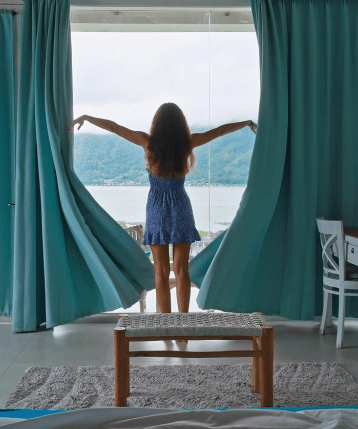 Woman opening curtains in a bright room