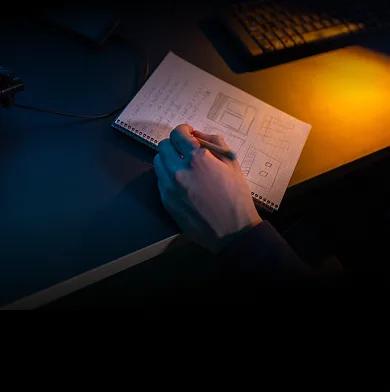 A person sketching page layouts in a notebook at a desk