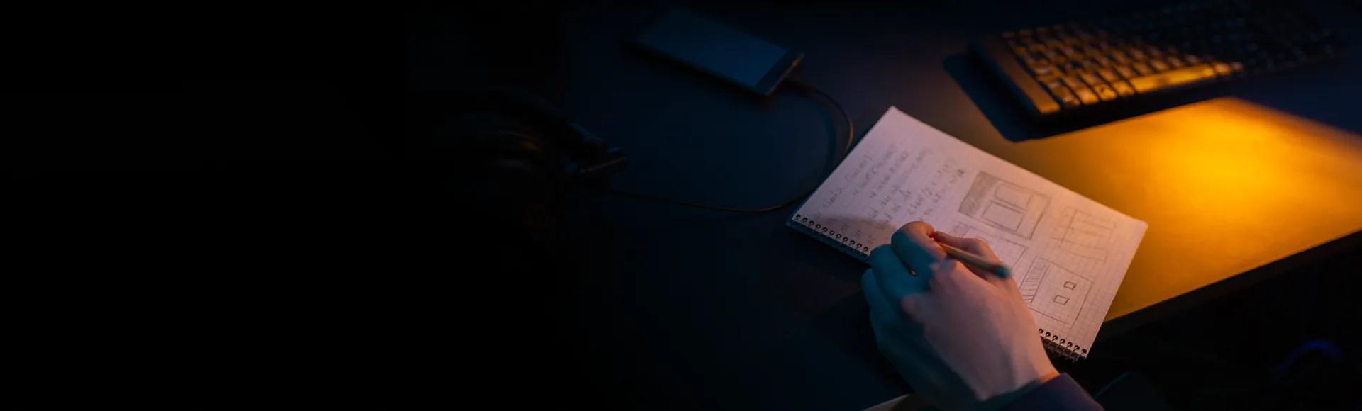 A person sketching page layouts in a notebook at a desk