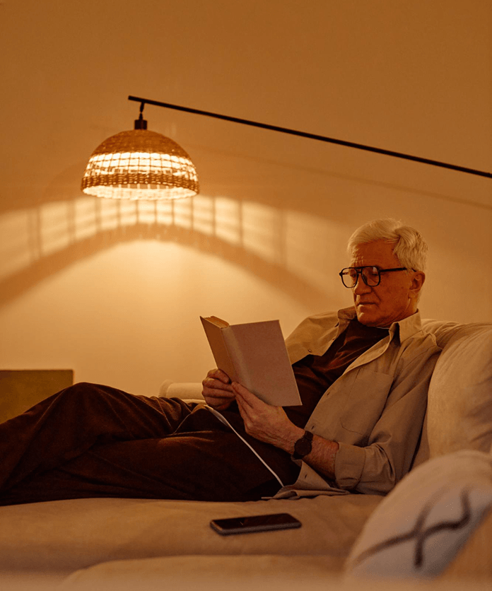 Man reading under floor lamp