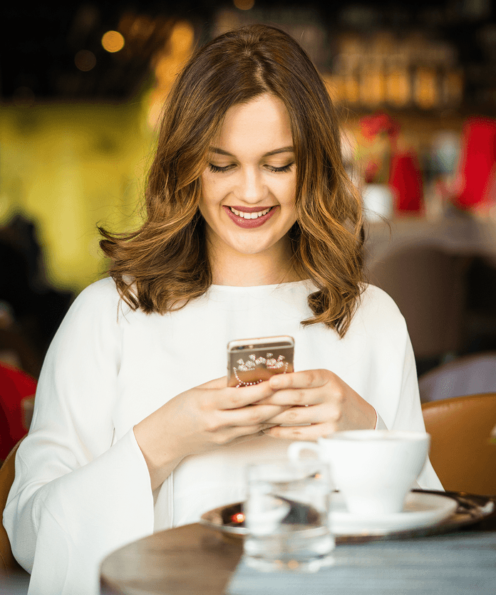Woman smiling using social media app at a cafe