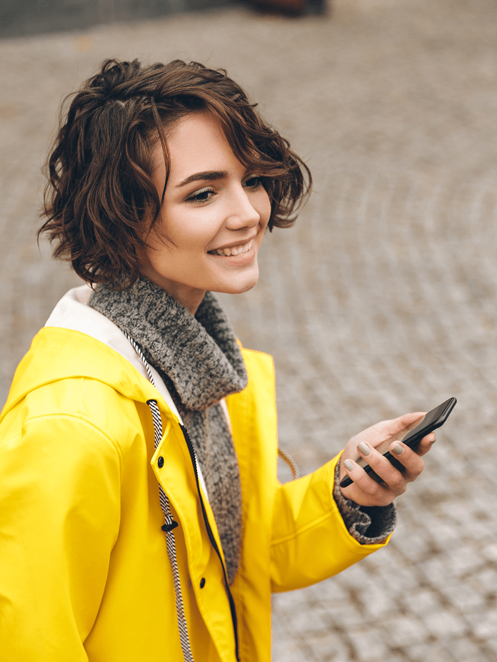 Woman in a yellow raincoat checking Thruhike on her phone